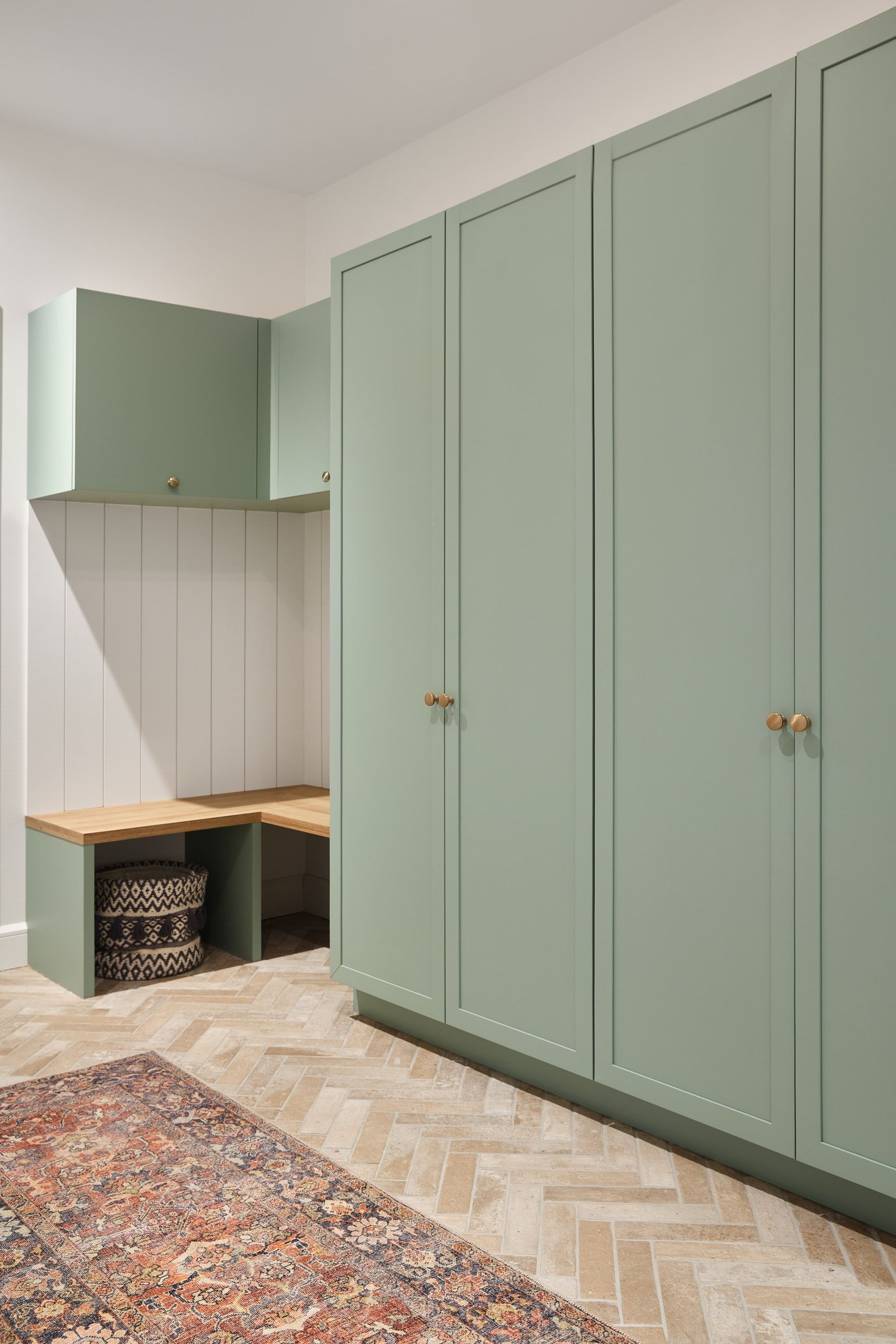 Un couloir avec des armoires vertes et un tapis.