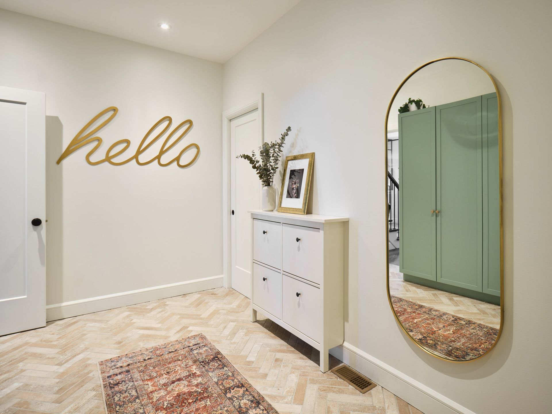 Un couloir avec un grand miroir et une commode.