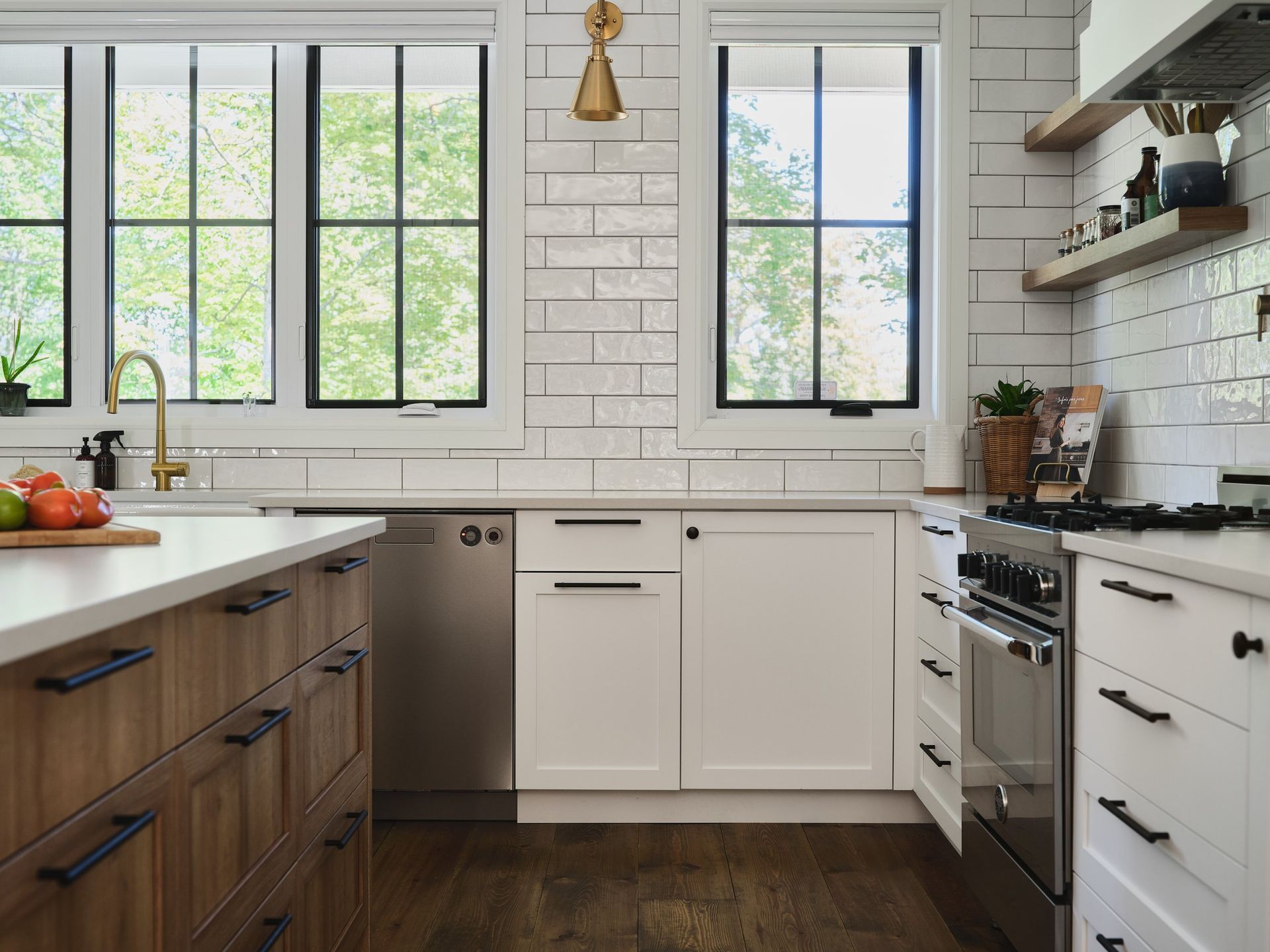 Une cuisine avec des armoires blanches, des appareils électroménagers en acier inoxydable, un évier et une cuisinière.