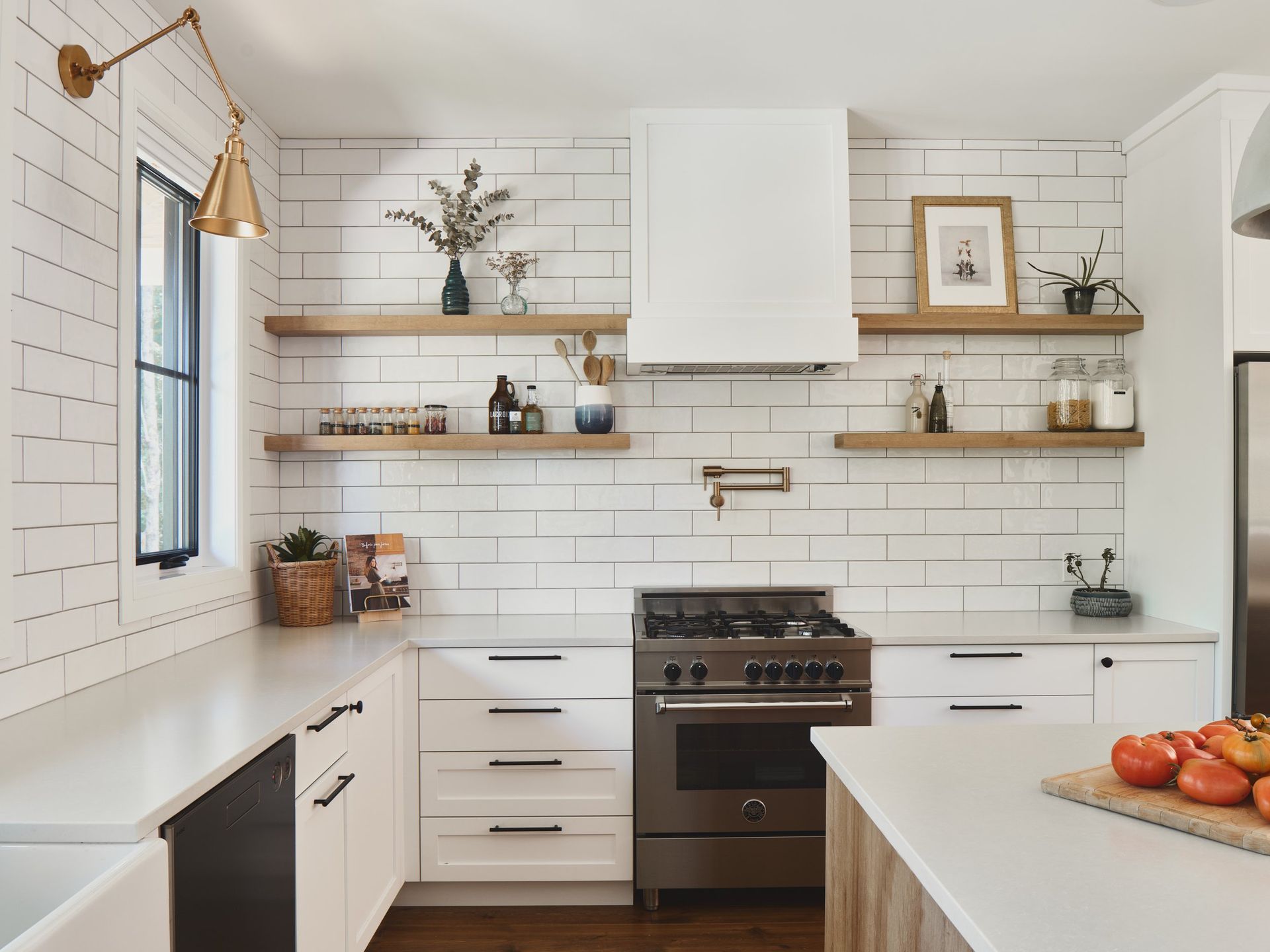 Une cuisine avec des armoires blanches, des électroménagers en acier inoxydable, une cuisinière et une fenêtre.