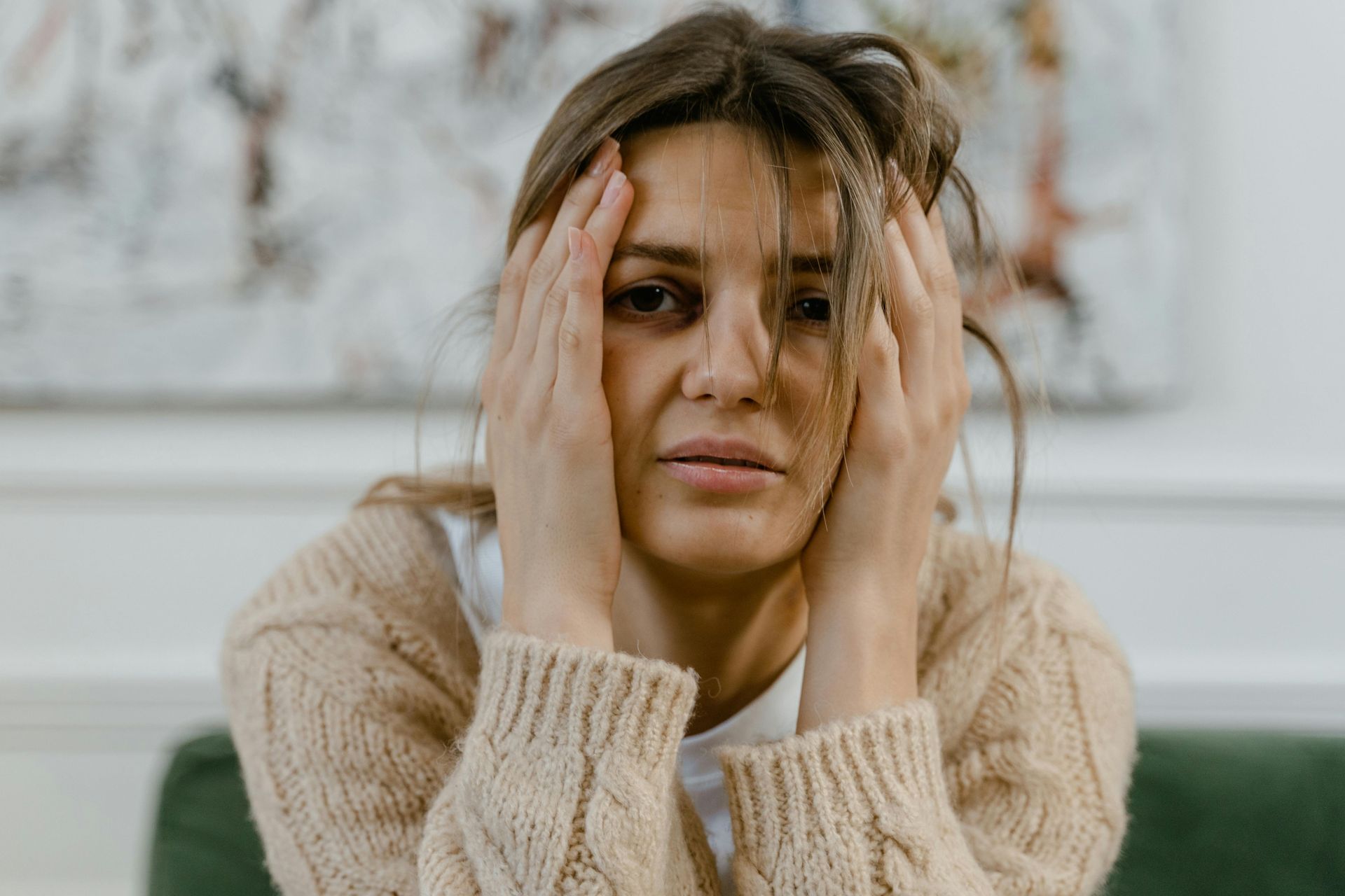 Close-up of a woman with her hands on her temples, looking distressed.