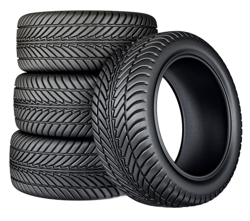 Stack of black car tires with one tire leaning in front