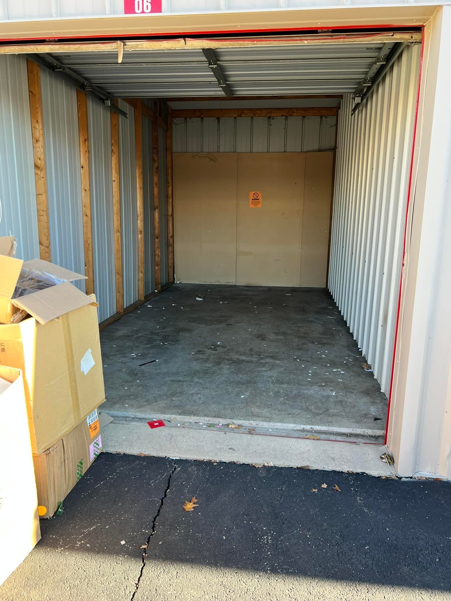 Empty storage unit with cardboard boxes on the left. The concrete floor and walls are visible.