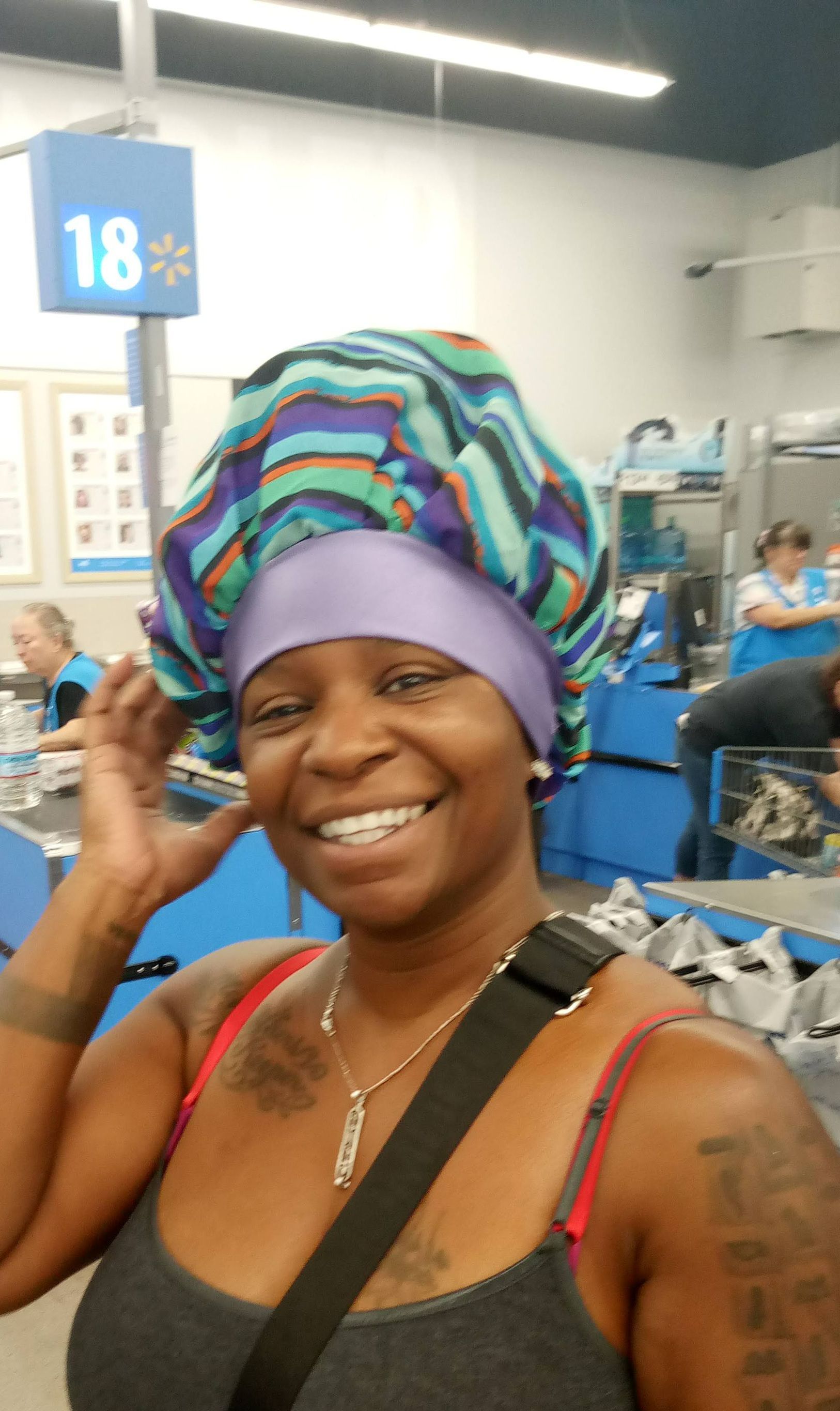 A woman wearing a purple bonnet is smiling in a store.