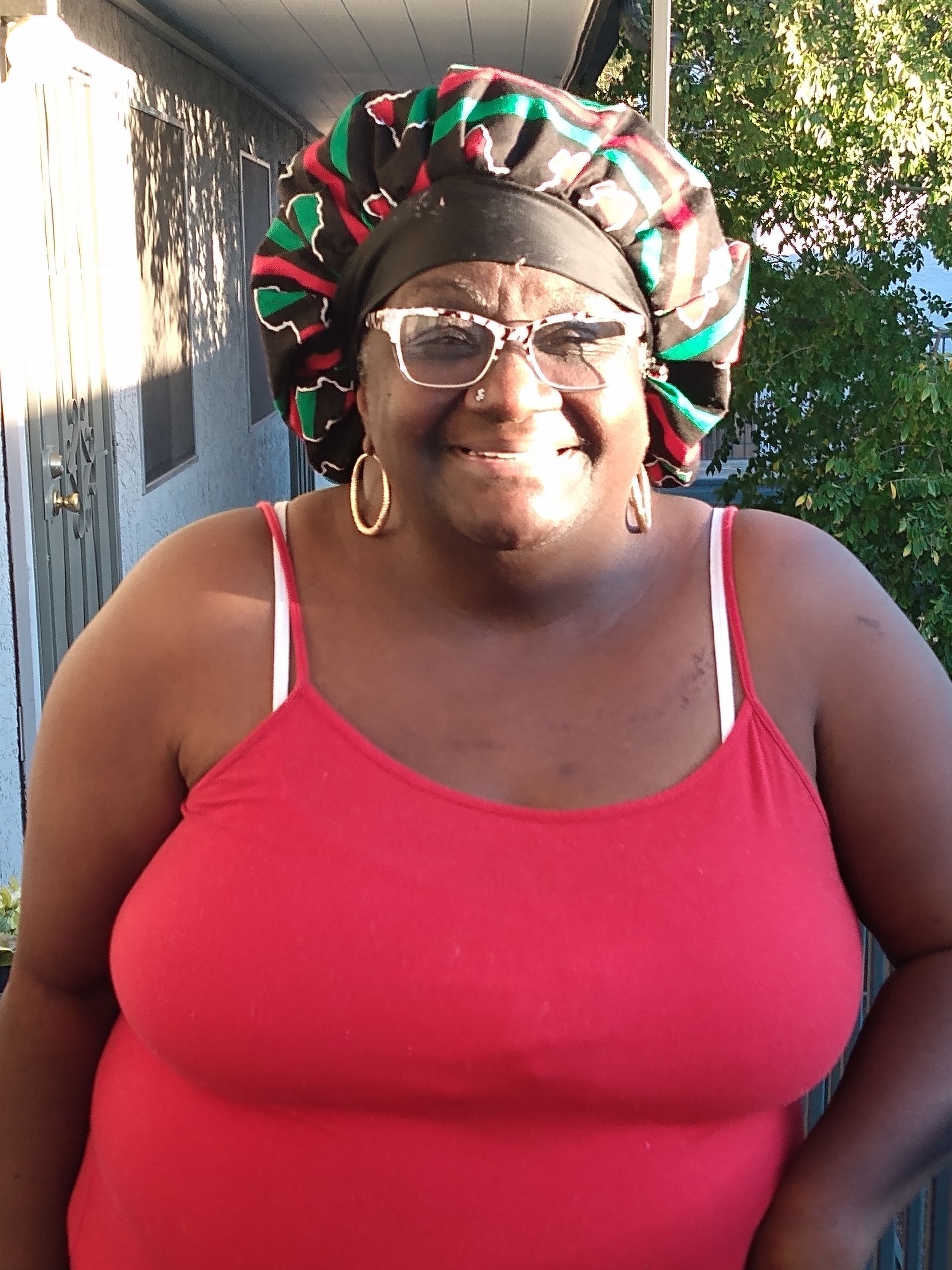 A woman wearing a red tank top and a bonnet is smiling