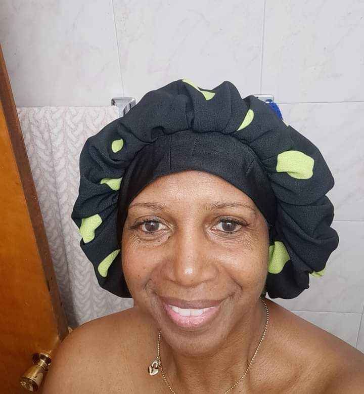 A woman wearing a black bonnet with green polka dots on it