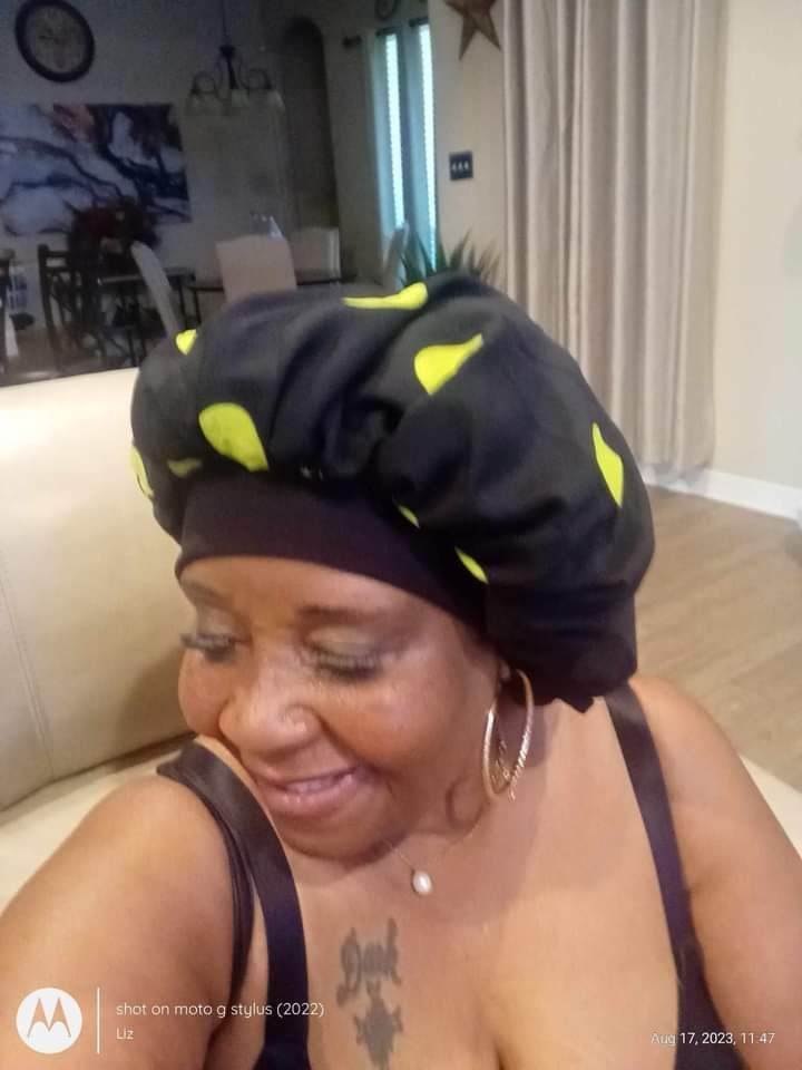 A woman wearing a black and yellow bonnet is sitting on a couch
