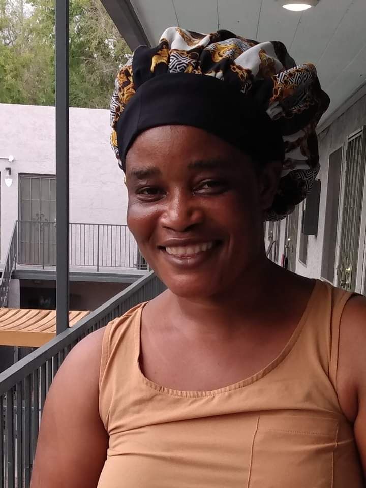 A woman wearing a bonnet a tank top smiles at the camera