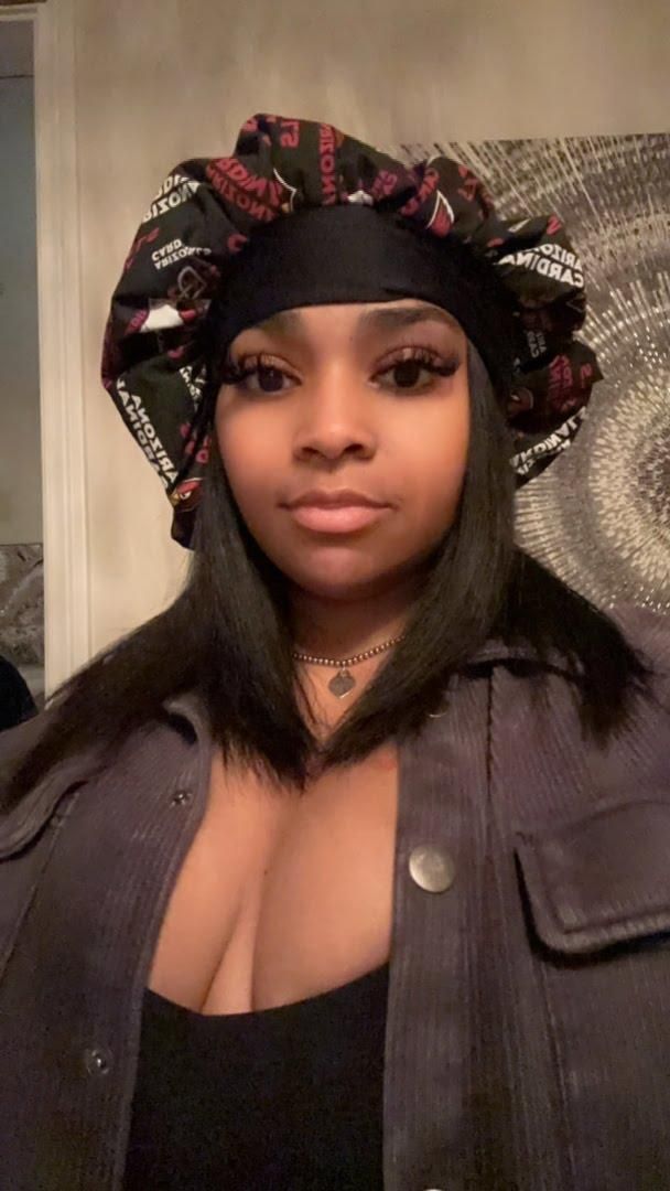 A woman wearing a bonnet and a jacket is standing in a room.