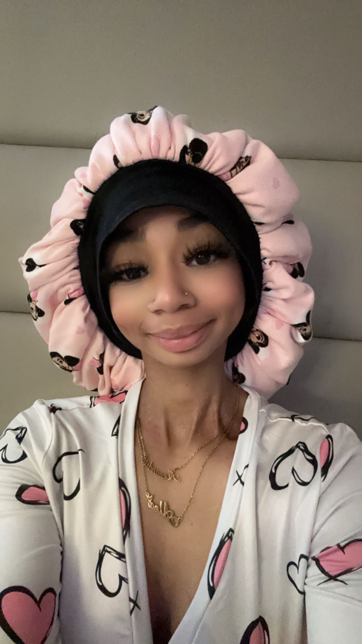 A woman wearing a pink and black bonnet is taking a selfie.