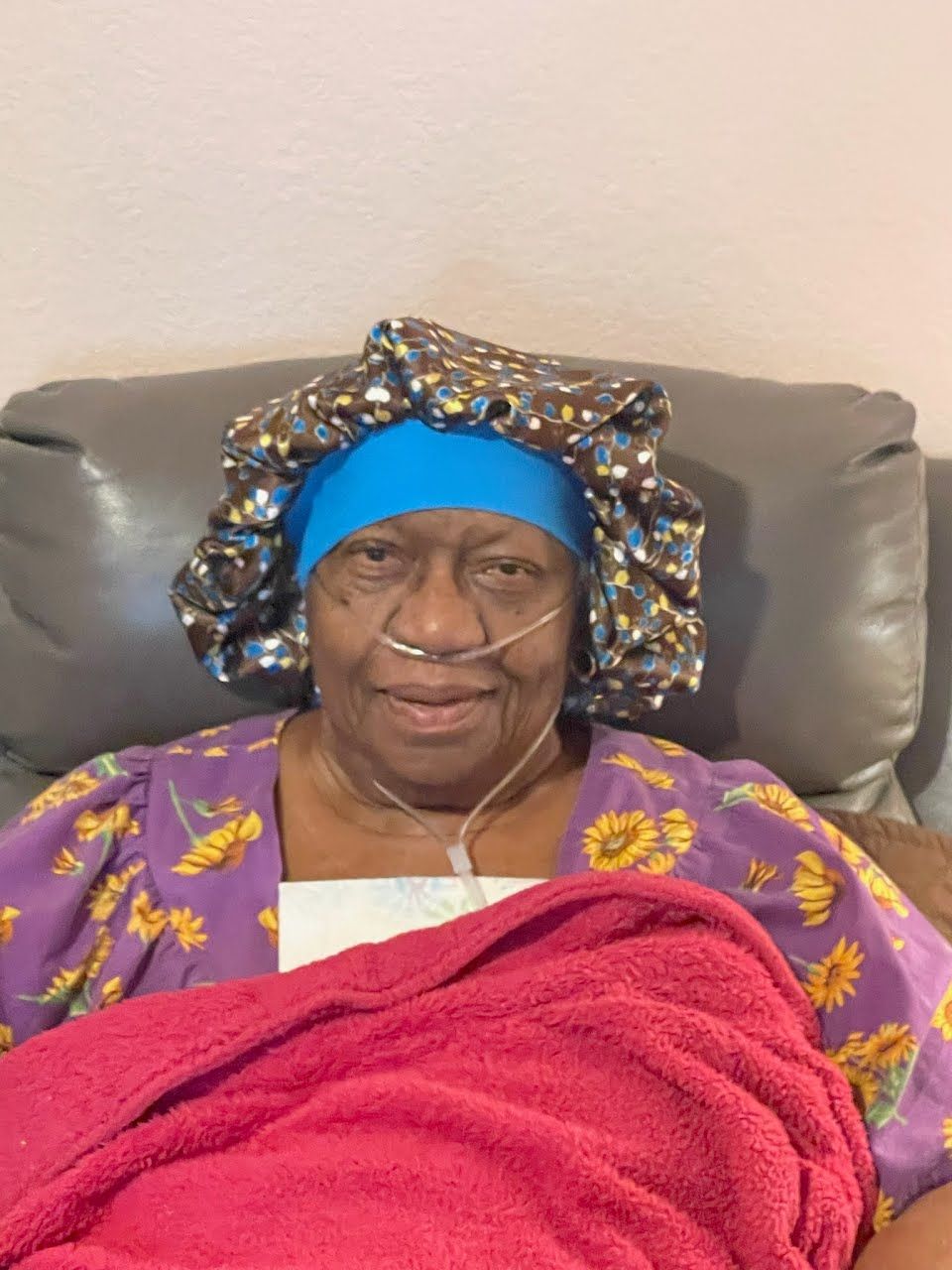 An elderly woman is laying in a chair wearing a bonnet.