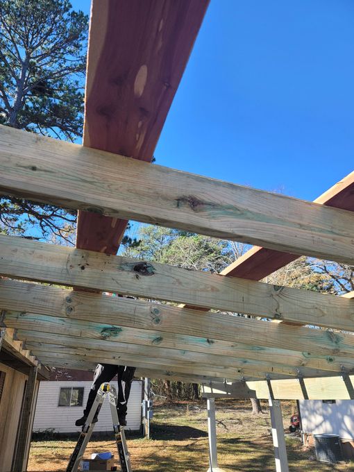 A person is standing on a ladder under a wooden structure.