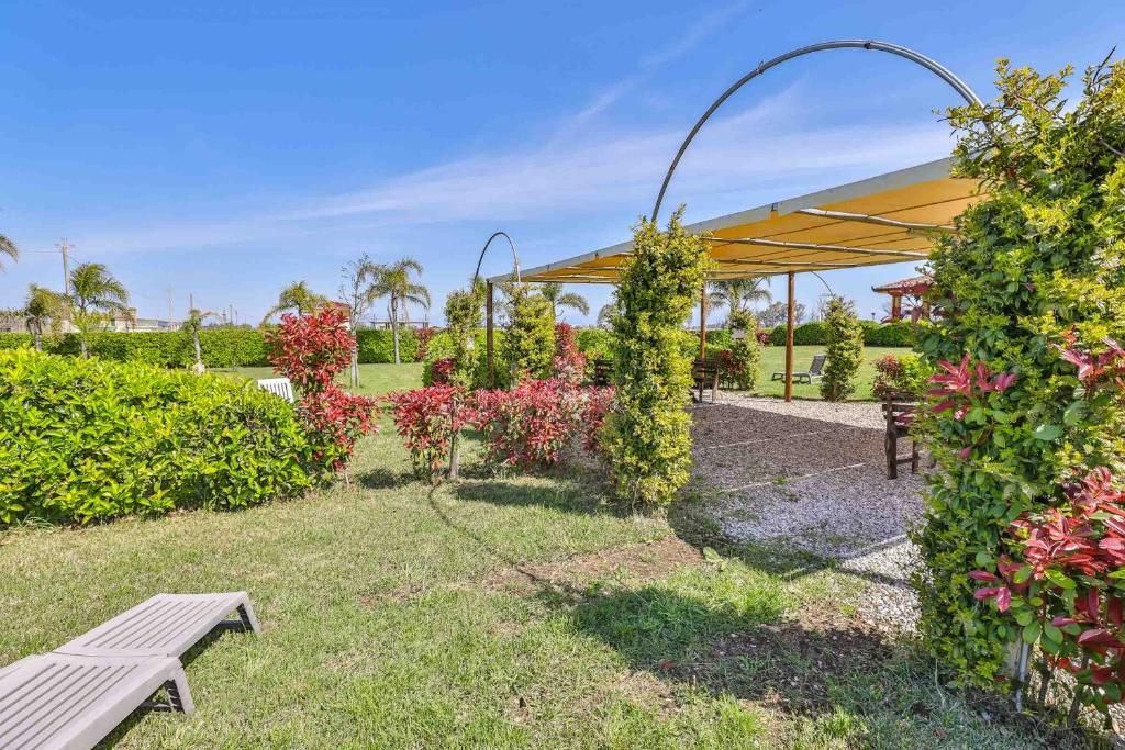 Un lussureggiante giardino verde con un pergolato e sedie in primo piano.