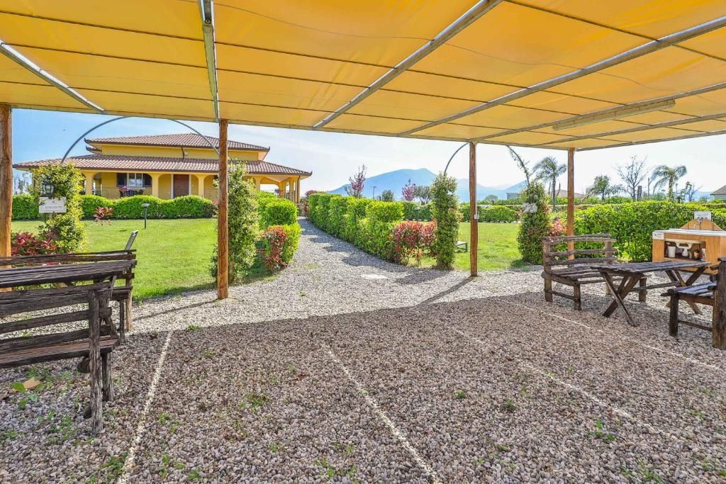 Un patio con tavoli e sedie sotto un ombrellone giallo.