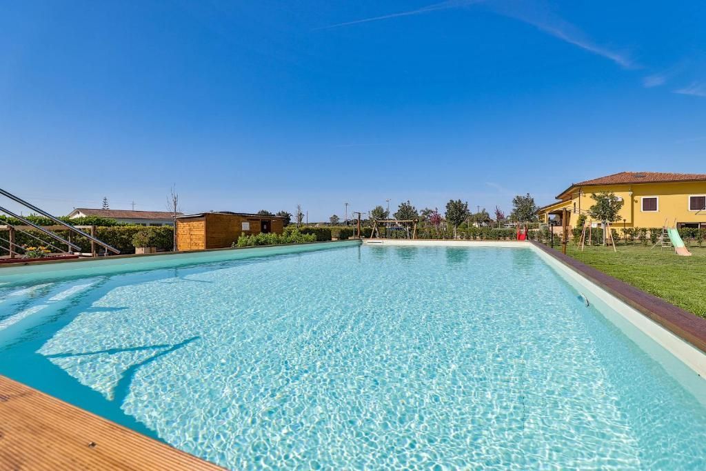 Una grande piscina con una casa gialla sullo sfondo.