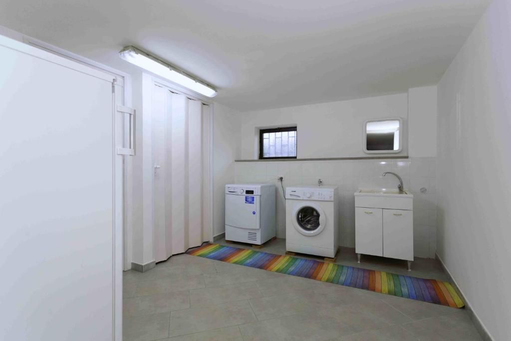 Una lavanderia con lavatrice, asciugatrice e lavandino.