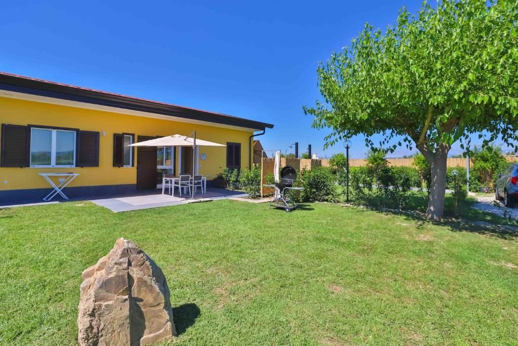 Una casa gialla con un grande prato davanti