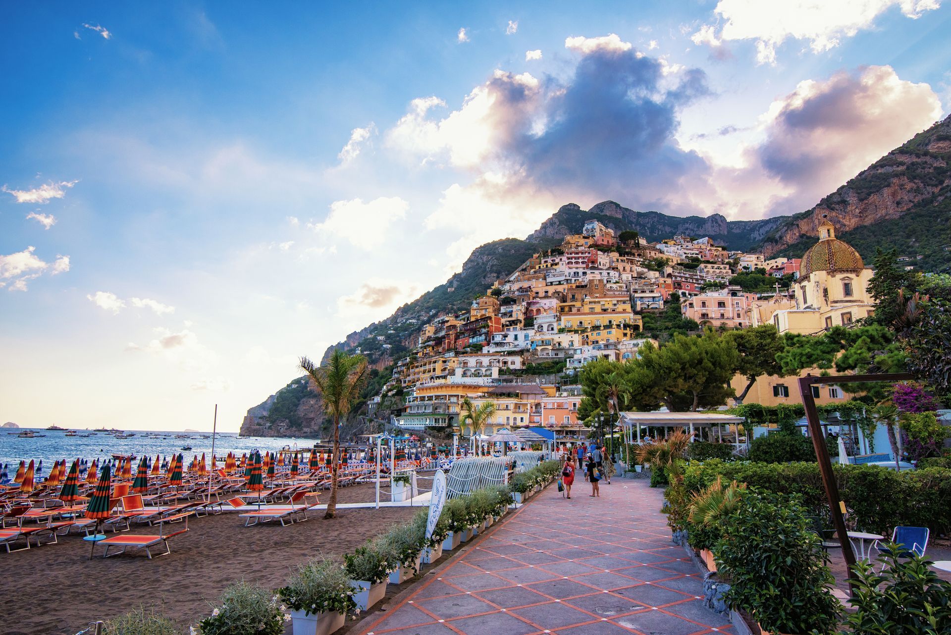 Un gruppo di persone sta camminando lungo un marciapiede vicino a una spiaggia.