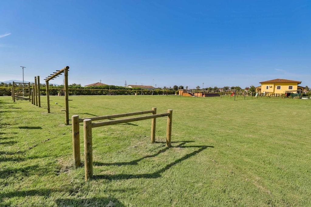 Un campo con una casa sullo sfondo e delle sbarre di legno al centro.