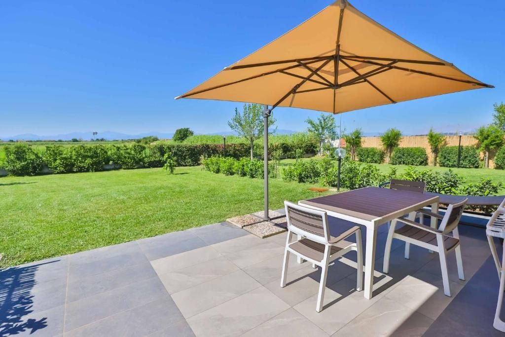 Un patio con tavolo e sedie sotto un ombrellone