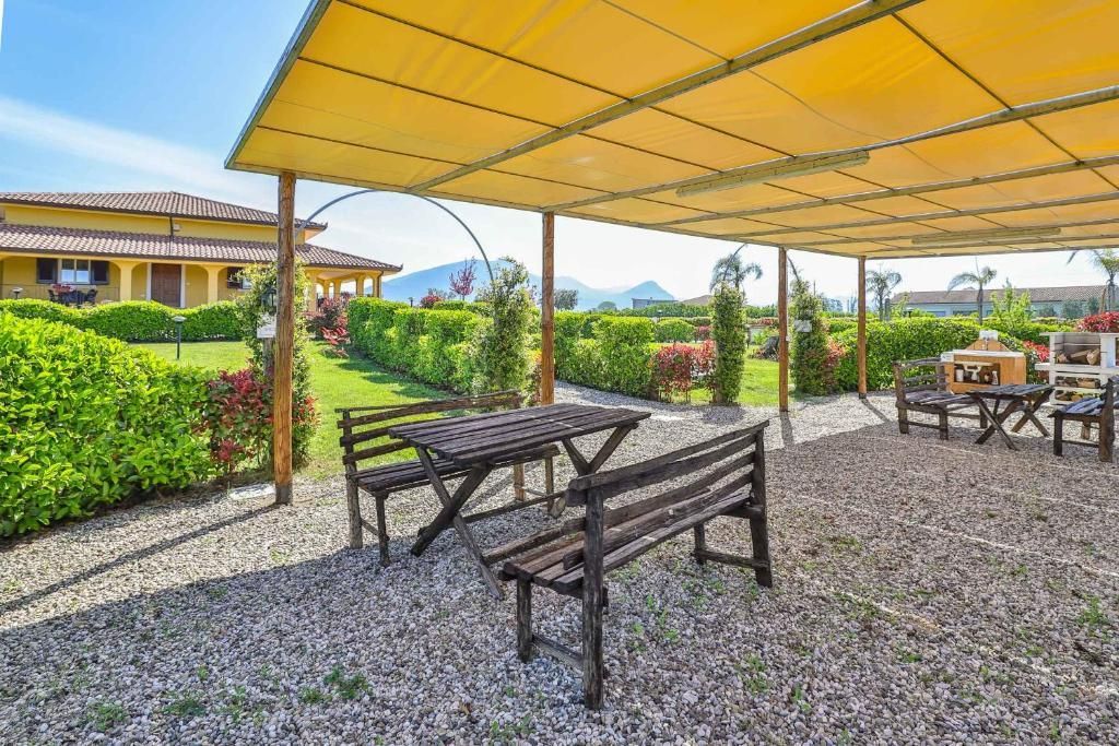 Un tavolo e una panca sotto un ombrellone giallo in una zona ghiaiosa.