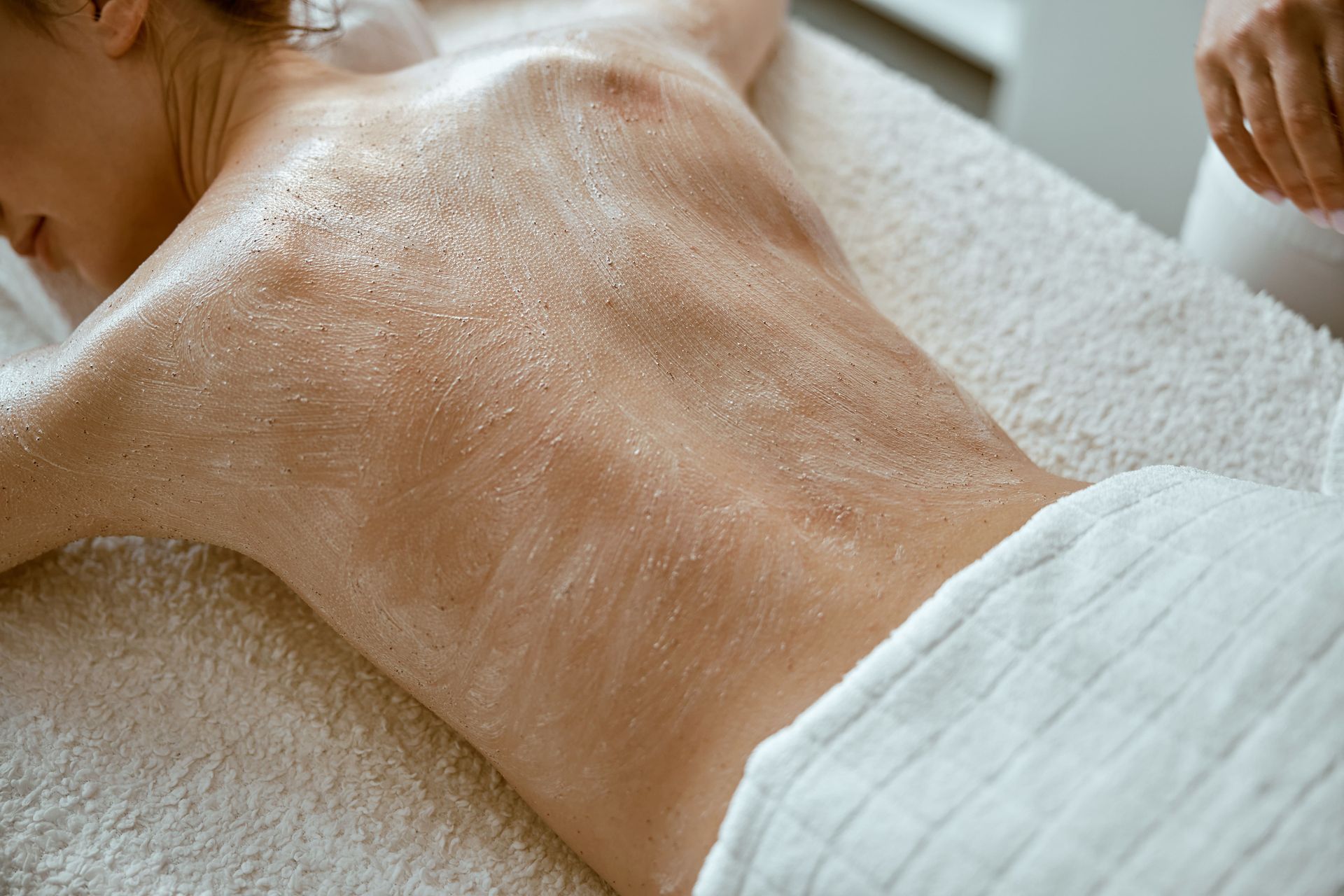 A woman is getting a body scrub at a spa