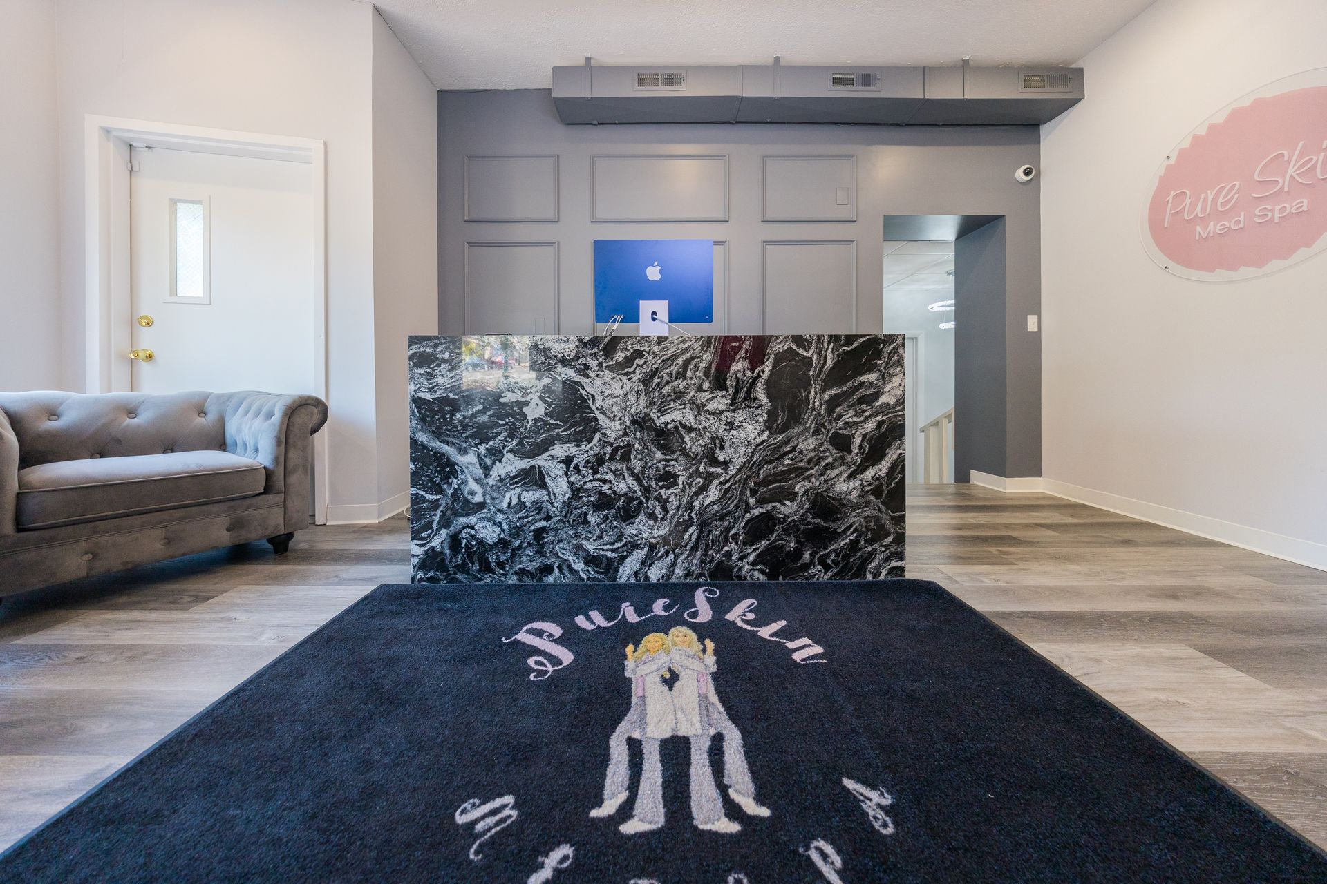 A reception area with a black rug and a couch