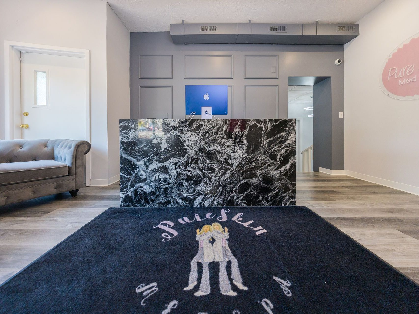 A reception area with a black rug and a couch