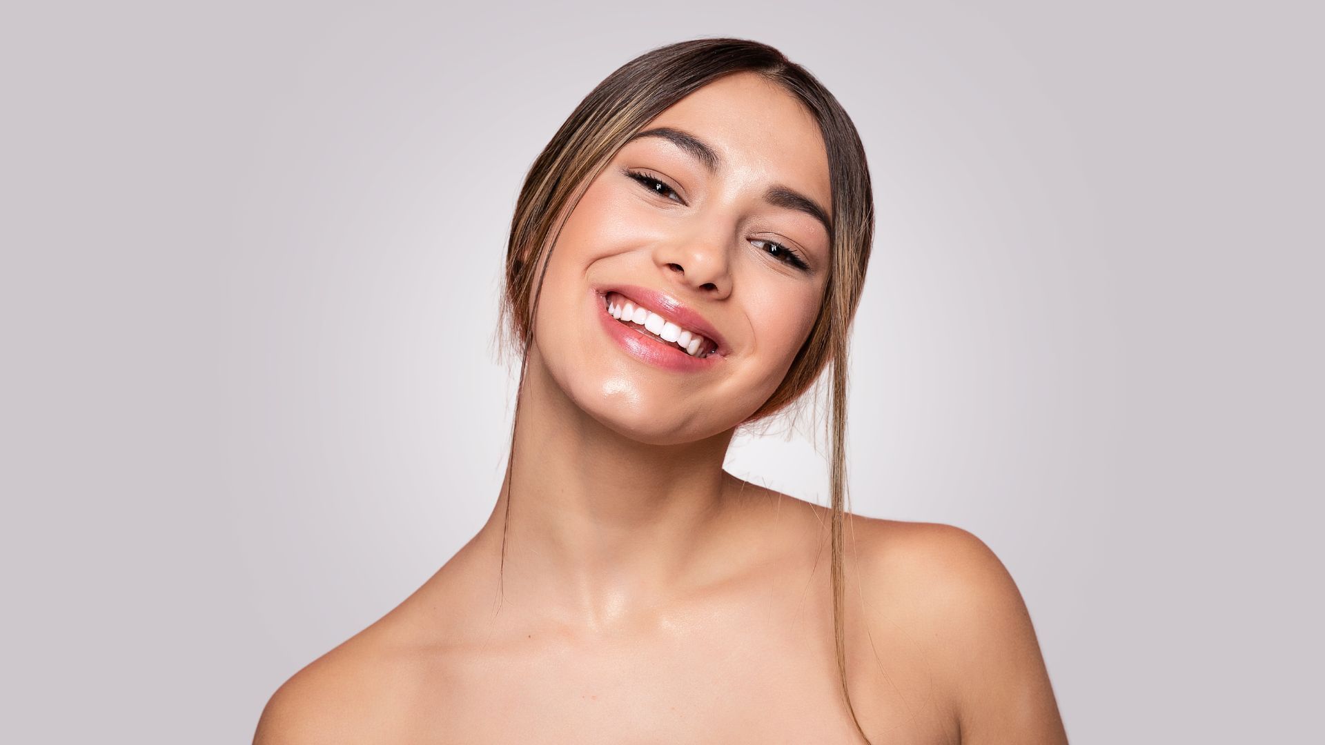 A woman without a shirt is smiling with her eyes closed.