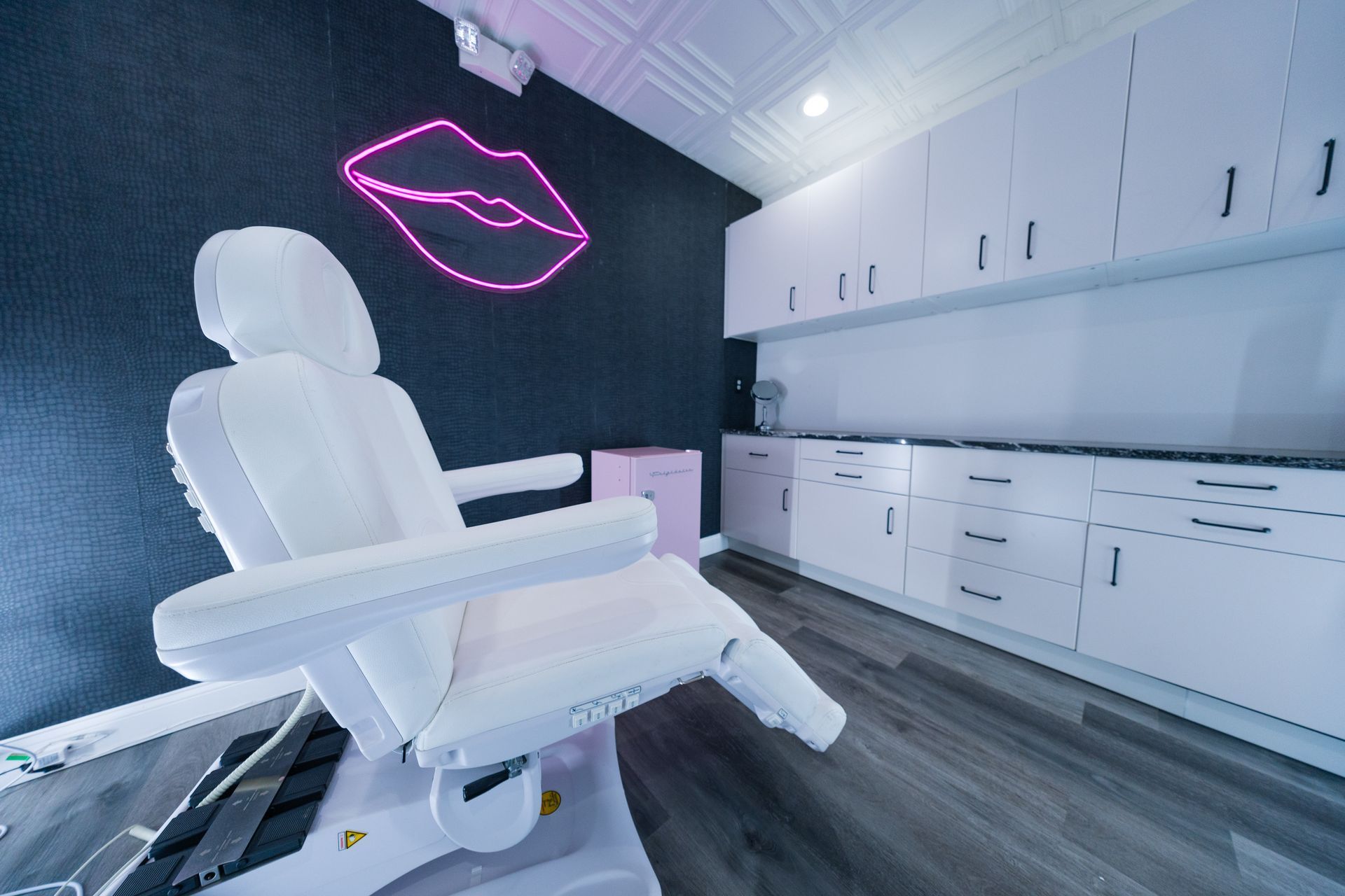 A white chair is in a room with a neon sign on the wall