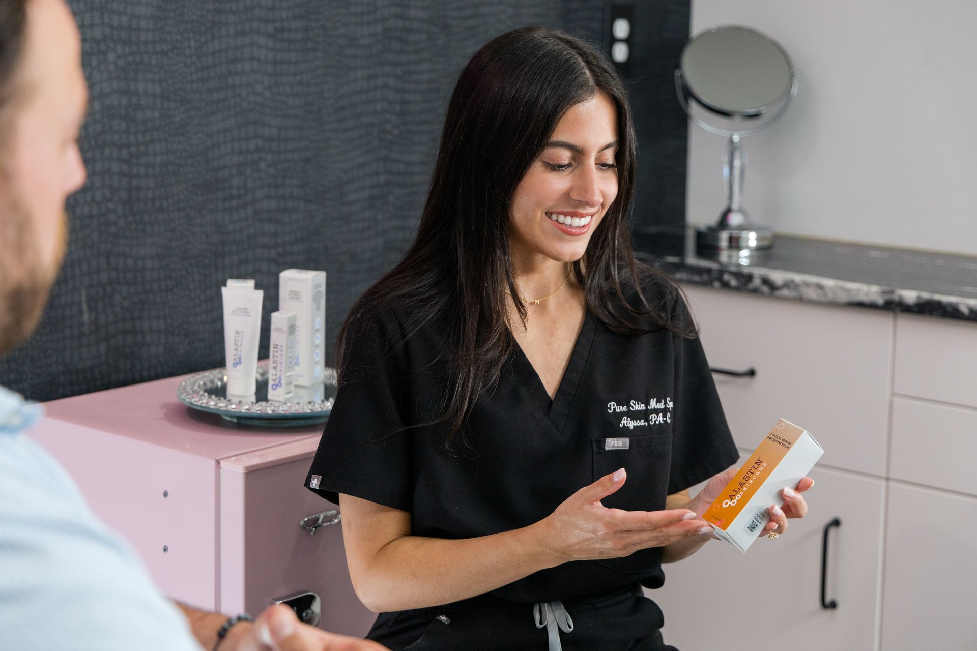 A woman is holding a box of lotion and talking to a man