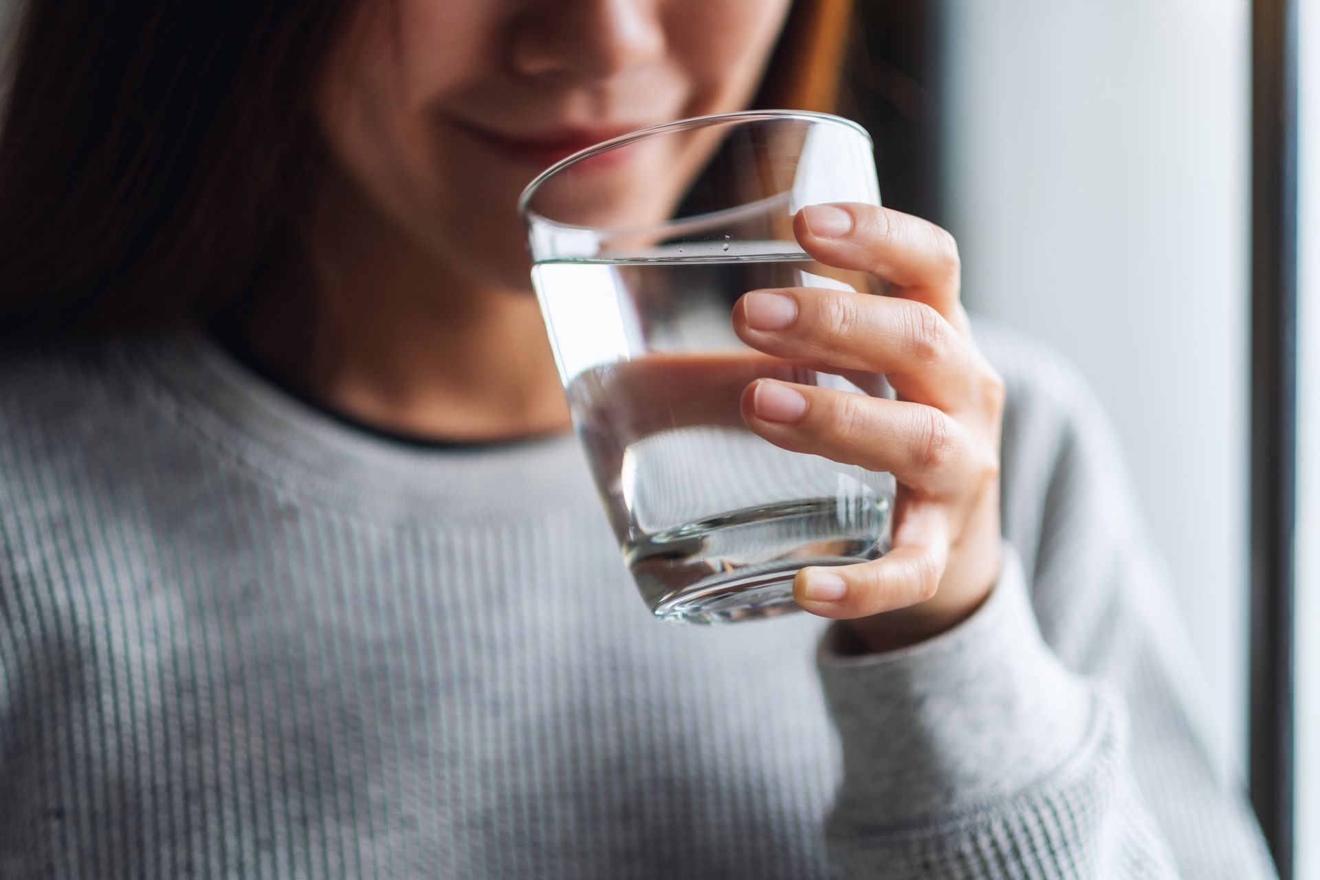 A woman is drinking a glass of water