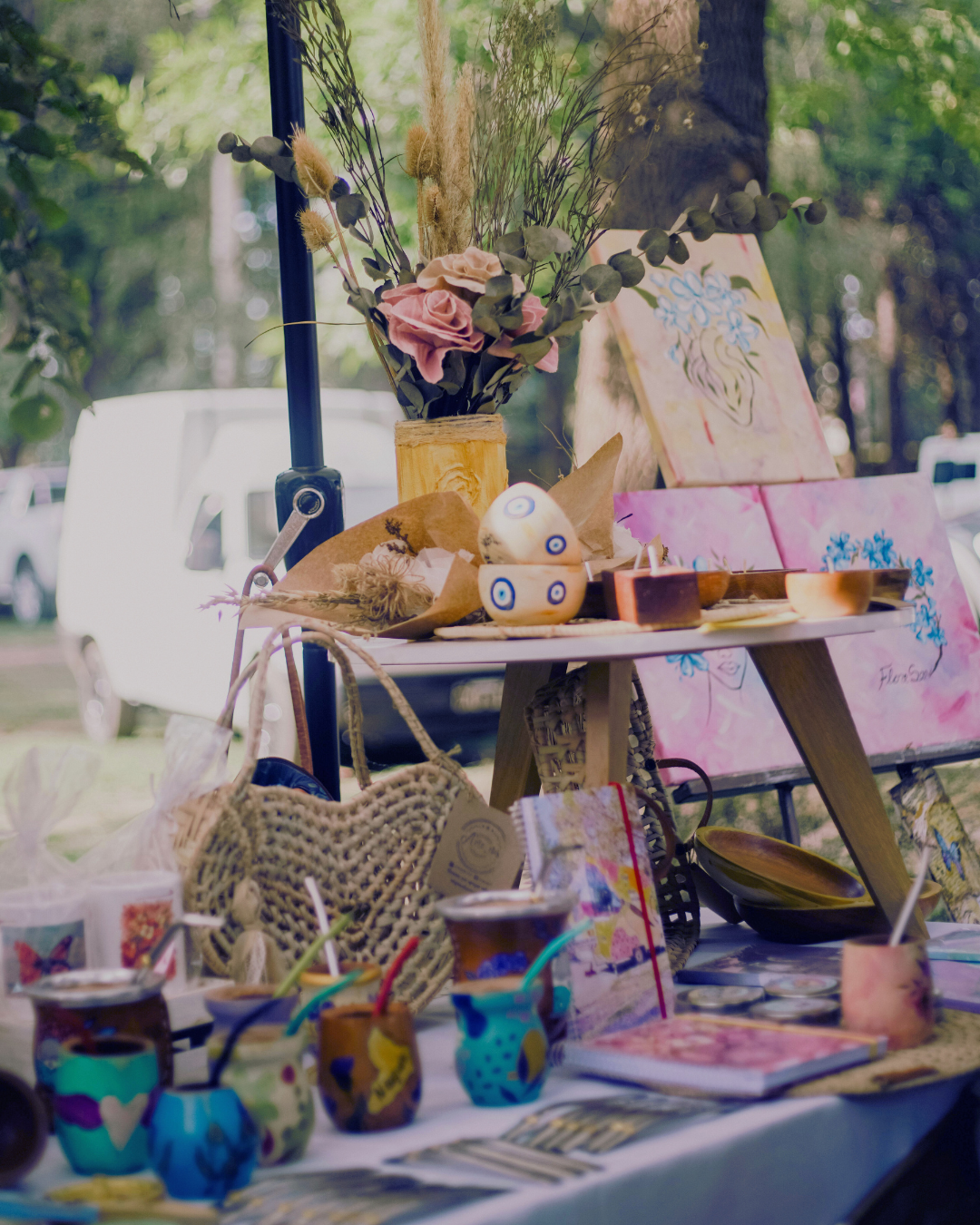 Artisan stall with craft items and mate cups. Bright colors, nature backdrop, fair.