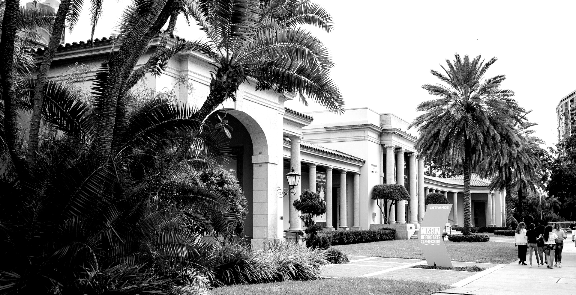 Black and white photo of a grand building with columns and palm trees, likely in a warm climate.