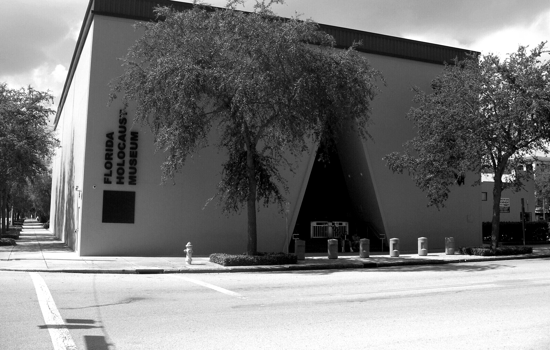 Florida Holocaust Museum exterior with trees, a sidewalk, and a street in black and white.