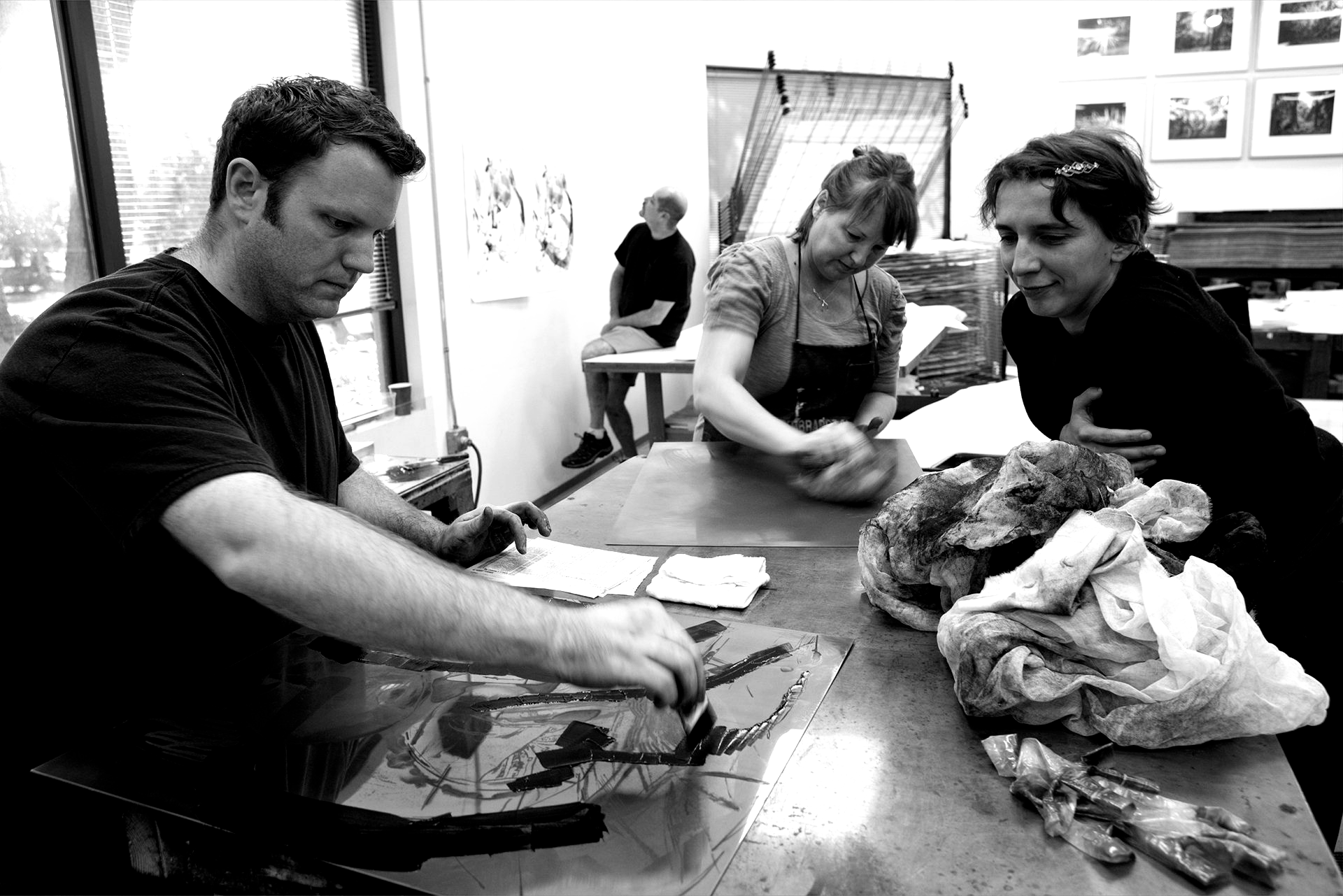 People working on art prints at a table in an art studio.