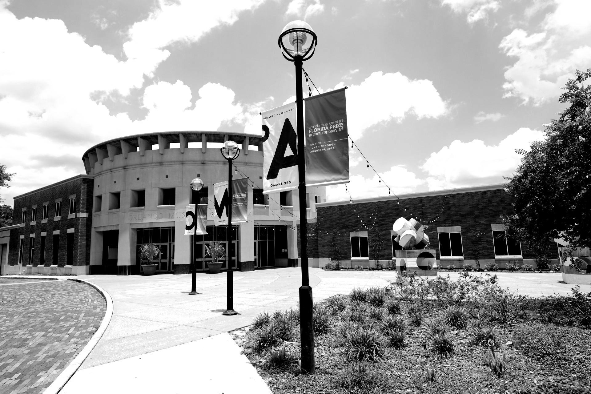 A black and white photo of a round building with banners hanging from lampposts in front.