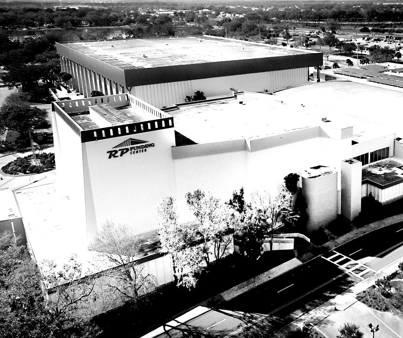 Aerial view of the RP Funding Center. Large, white building with a flat roof, surrounded by trees and roads.