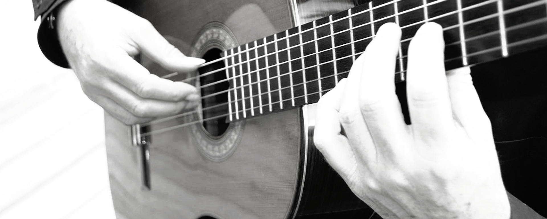 A person's hands playing a classical guitar.