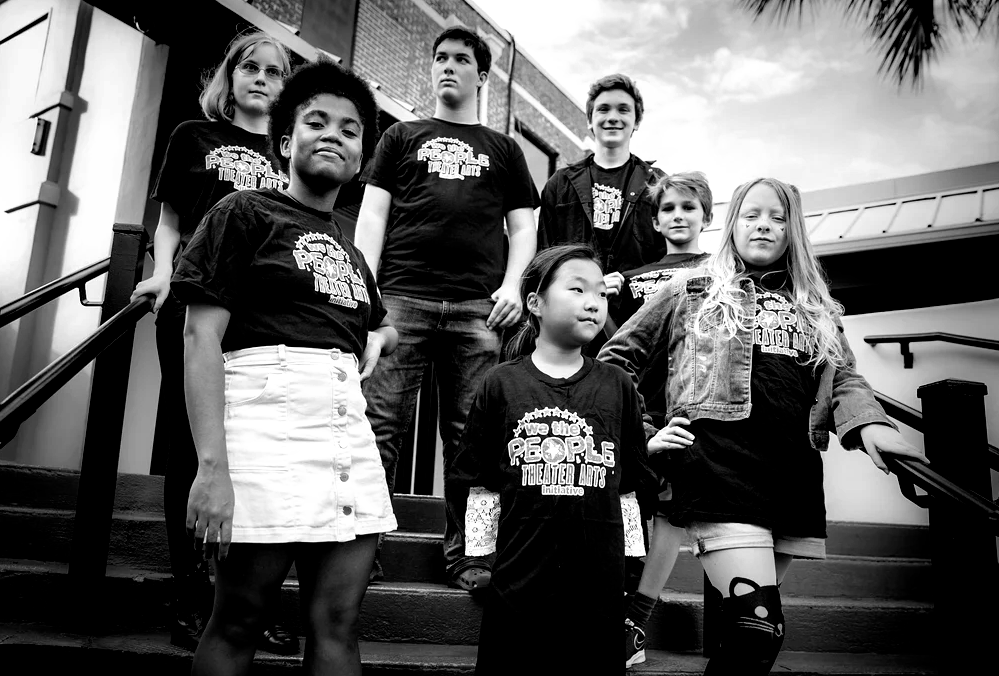 Group of students wearing matching shirts, posing on outdoor stairs in black and white.