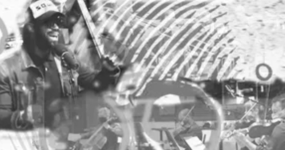 Man speaking into microphone; partial view of crowd and structure in background.