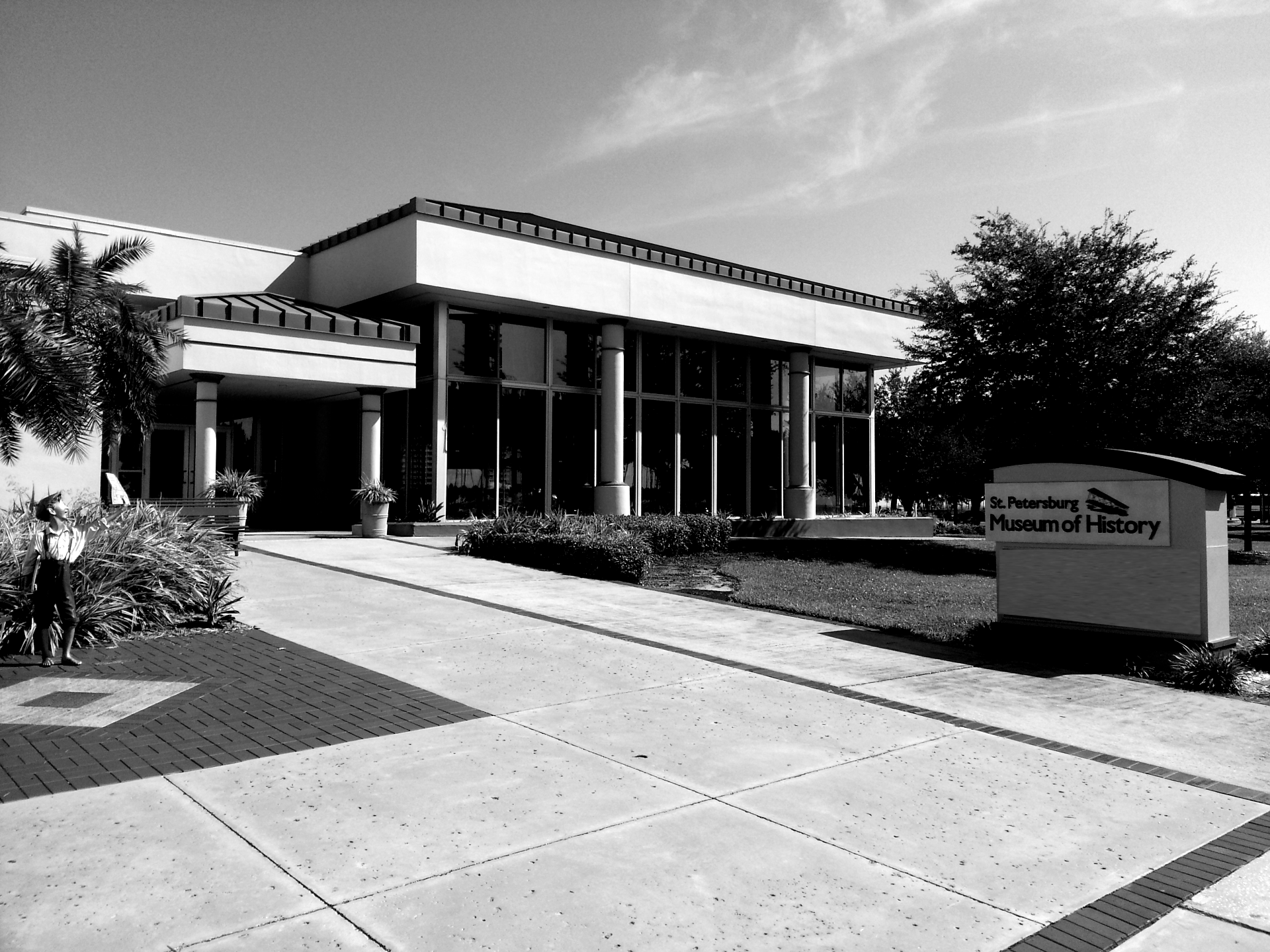 St. Petersburg Museum of History building, black and white. Wide, glass front, sign on lawn.