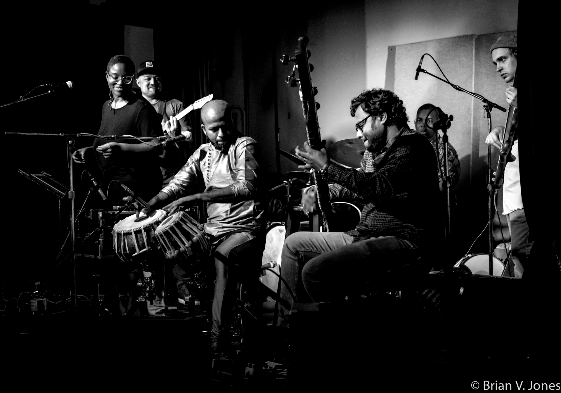 Black and white photo of a band performing on stage with various instruments.