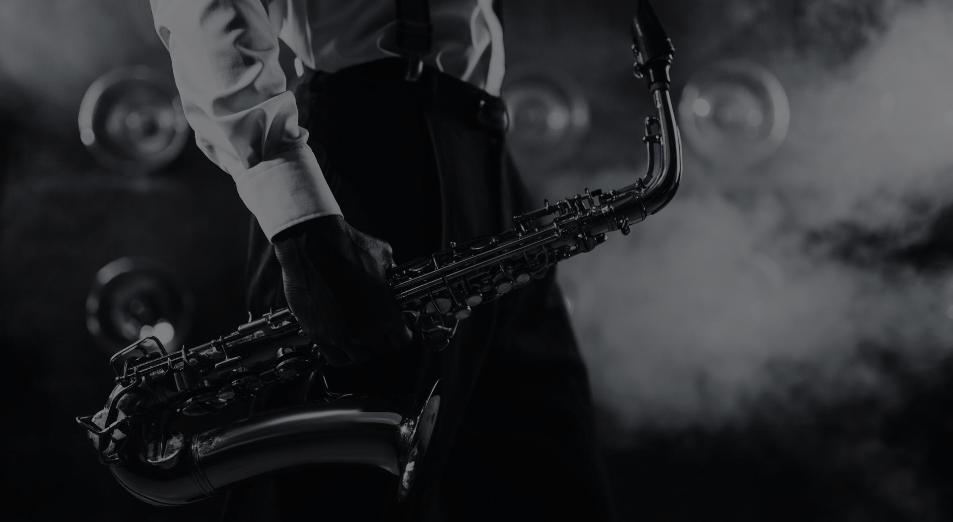Saxophone player, black and white, holding instrument in a smoky setting.