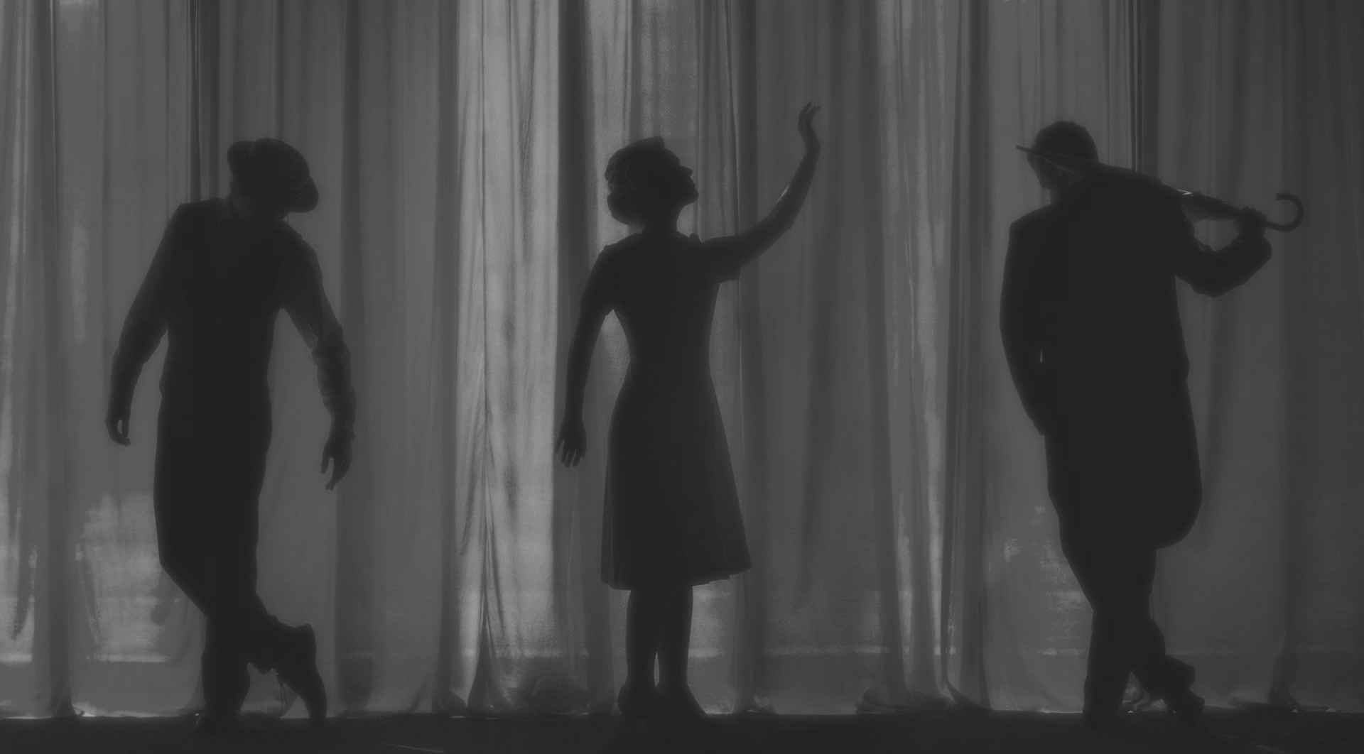Silhouetted figures: a man dancing, a woman raising an arm, and a man with an umbrella.