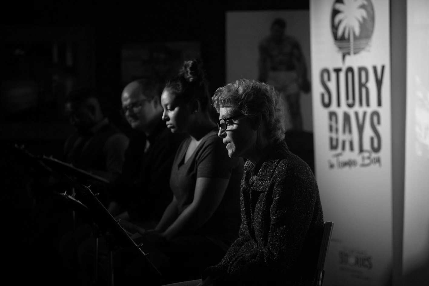 People reading scripts at Story Days event, black and white.