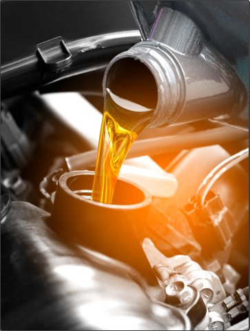 Motor oil pouring into an engine, with a warm orange glow in the background | Autotrendz