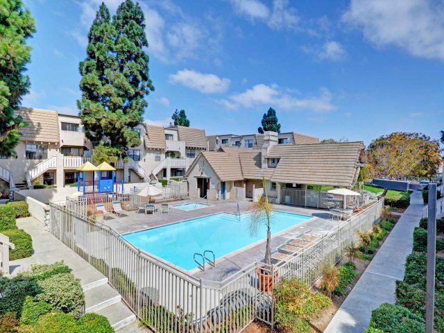 A large swimming pool surrounded by a fence in front of a building.