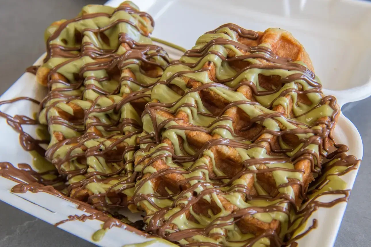 A waffle with blueberries and almonds on a plate with a fork