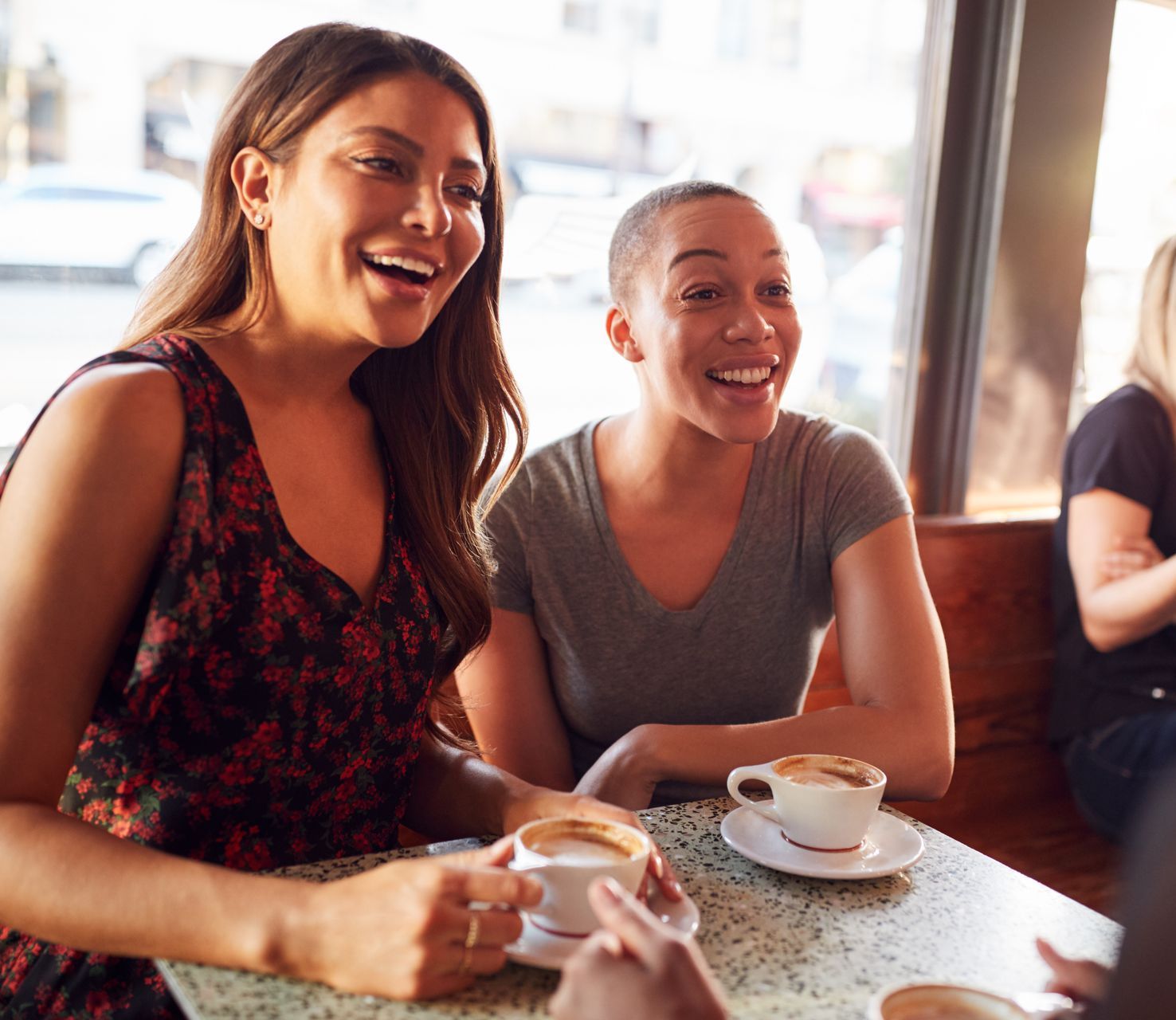 A group of women are sitting at a table in a cafe drinking coffee.